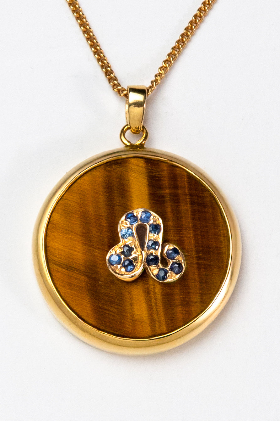 Leo zodiac pendant: tiger's eye cabochon and blue sapphire.

Amuleto de Leo: ojo de tigre cabujón y zafiro azul.